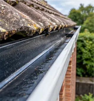 The same gutter after cleaning, clear of leaves and moss with water running along it